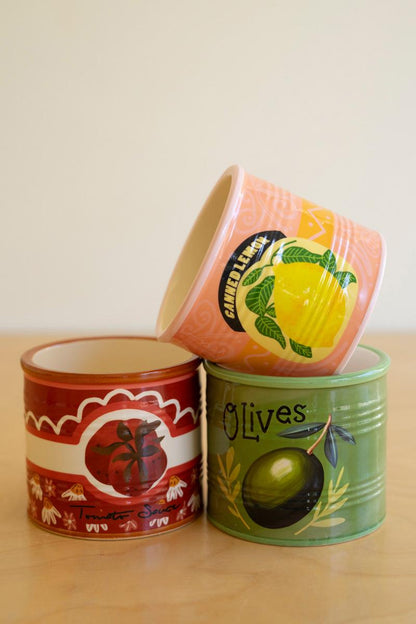 Three decorative planters with fruit-themed designs on a wooden surface.
