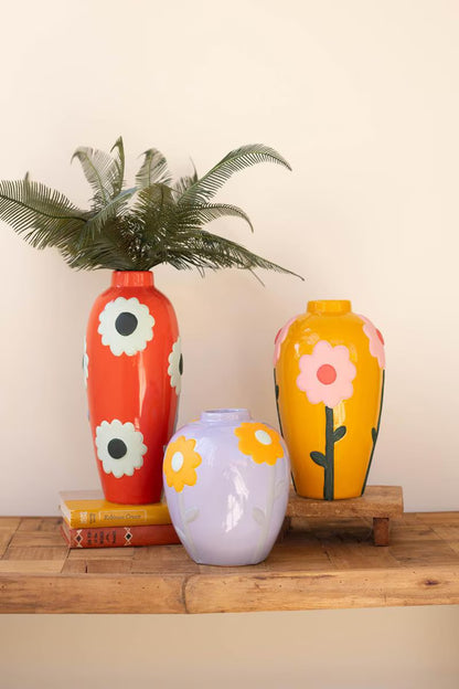 Three colorful ceramic vases with floral designs on a wooden surface.