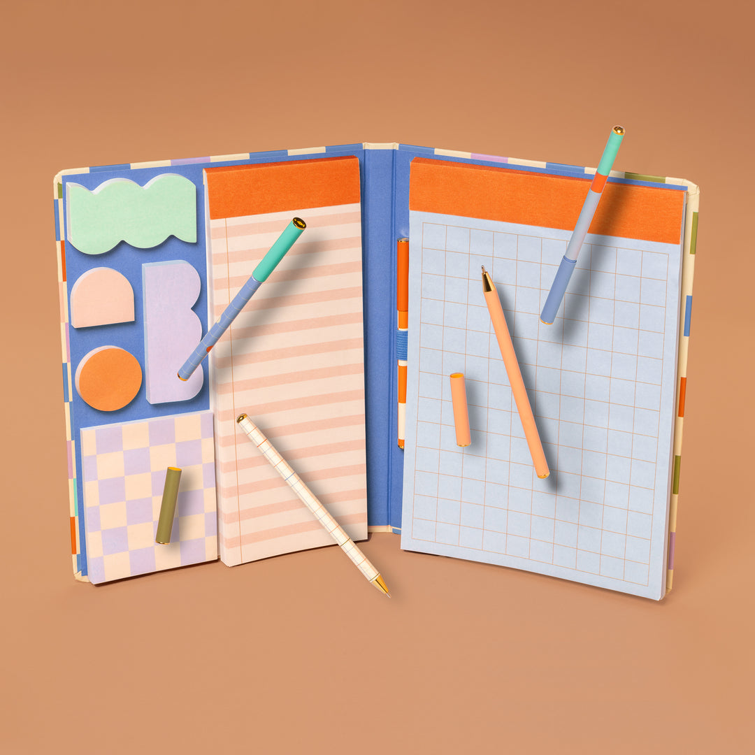 notebook open showing pen, sticky note, and other note pad arranged on an orange background