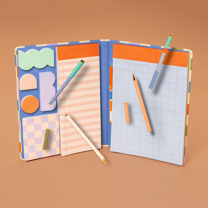 notebook open showing pen, sticky note, and other note pad arranged on an orange background