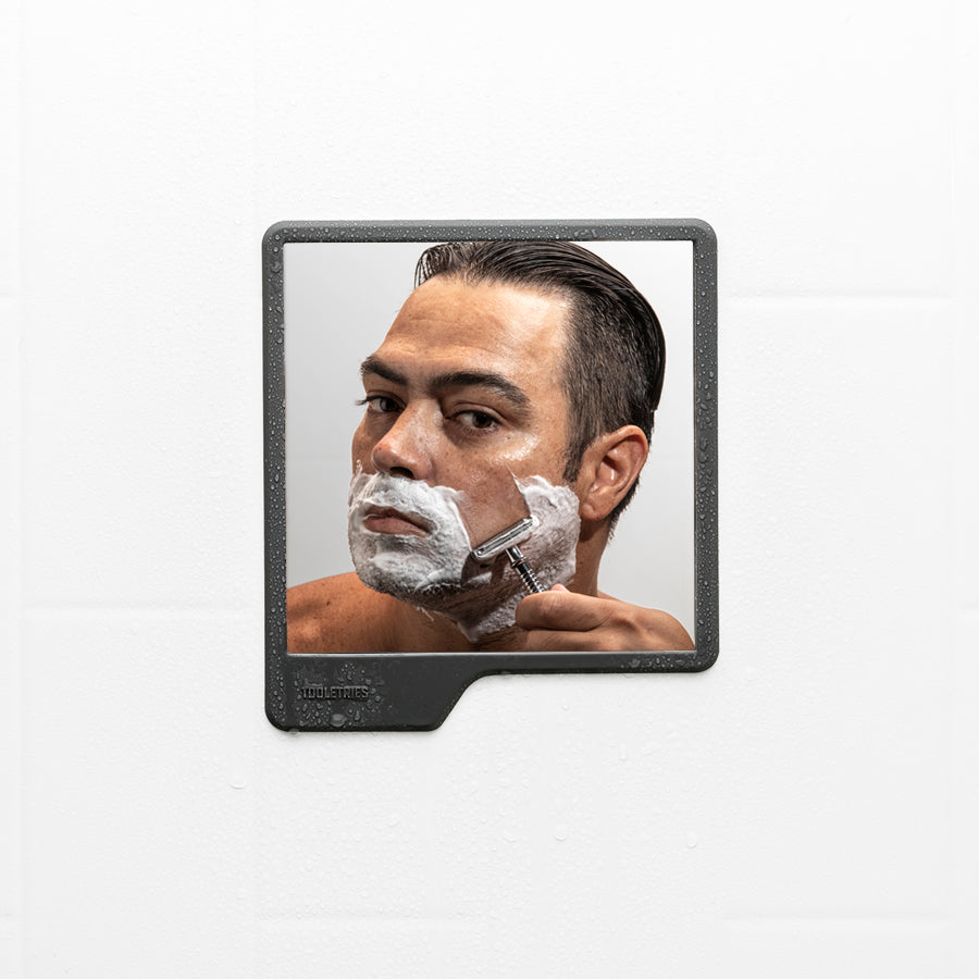 reflection of person shaving in shower mirror.