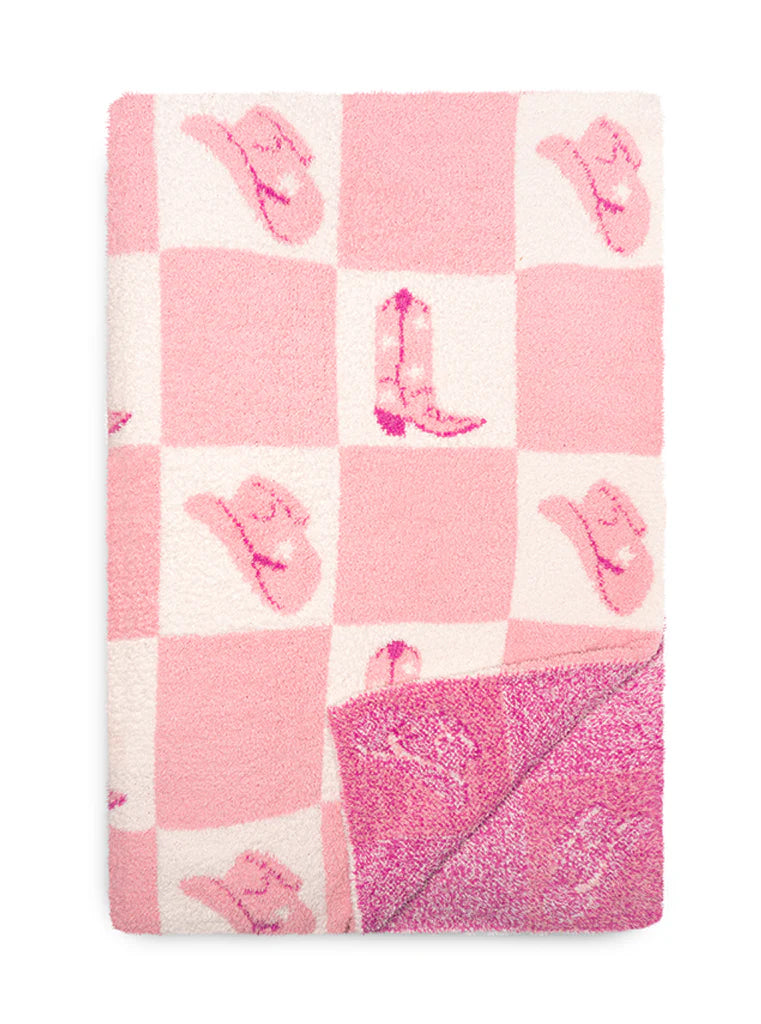 folded pink and white check blanket with boots and hats printed on it.