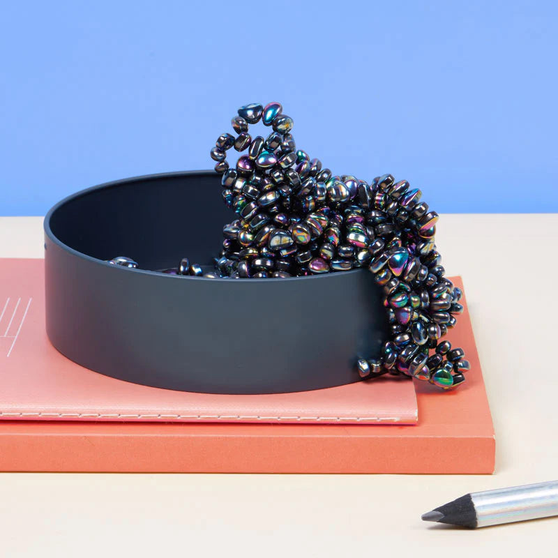 oil slick crags spilling out of their tin set on a stack of books