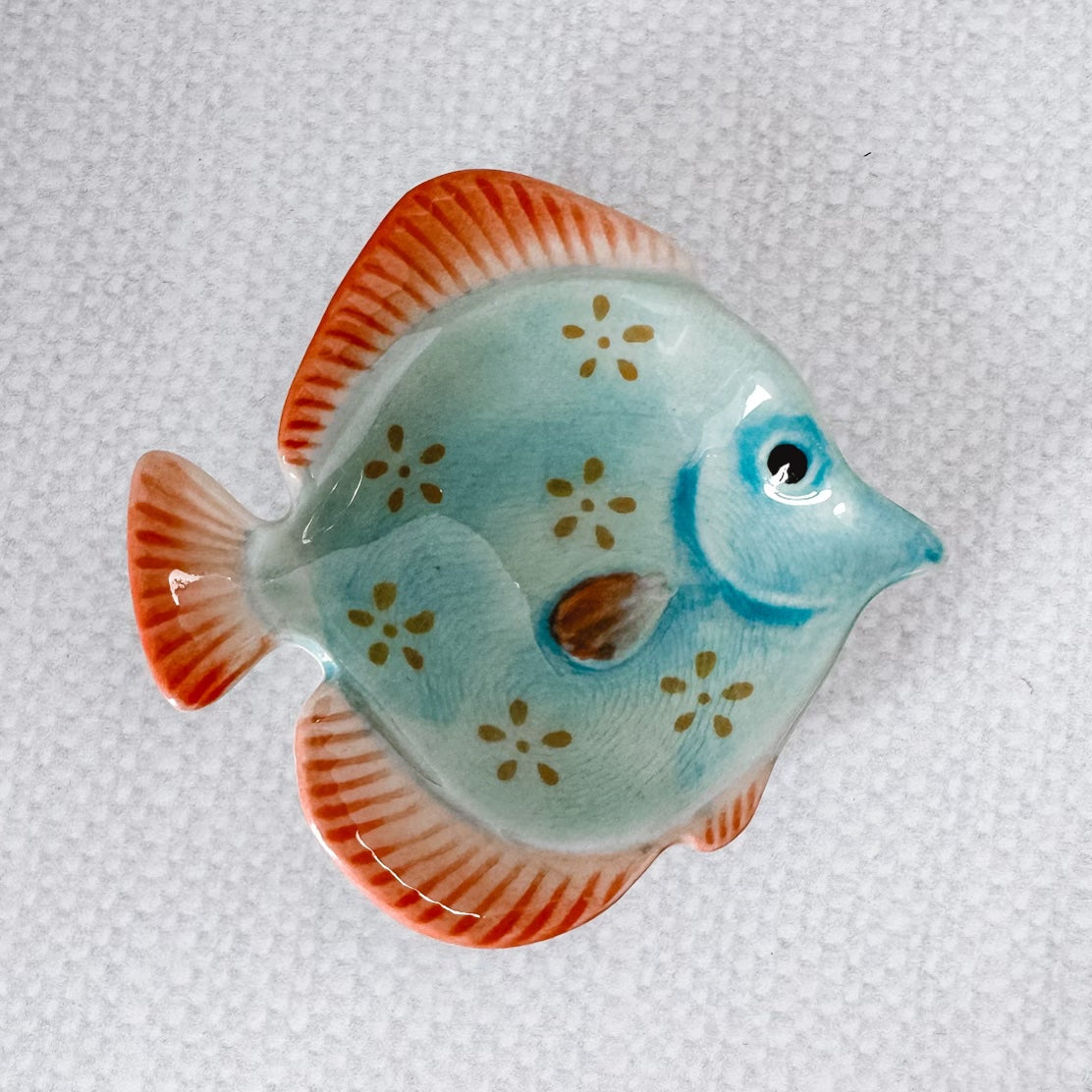 blue fish with little green flowers and orange fins.