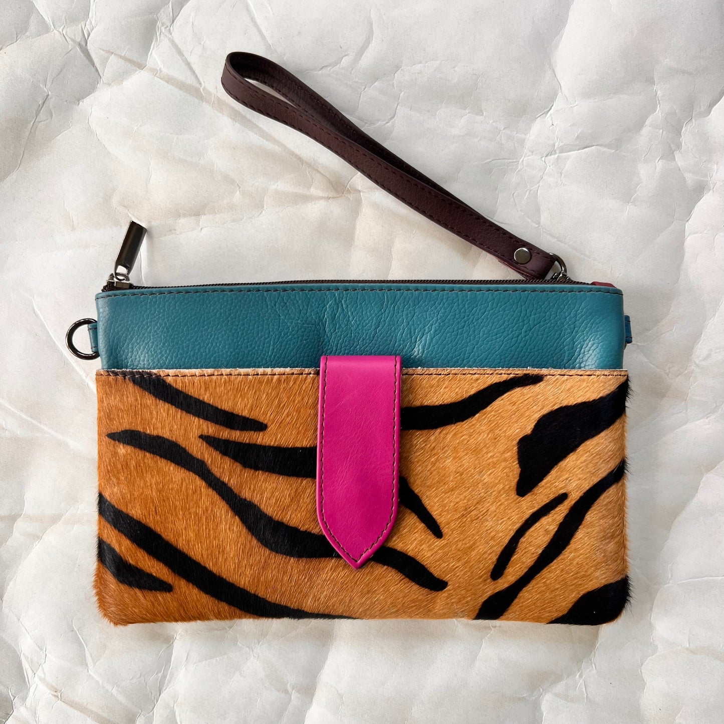 turquoise rectangular bag with cheetah print pocket, brown wristlet strap.