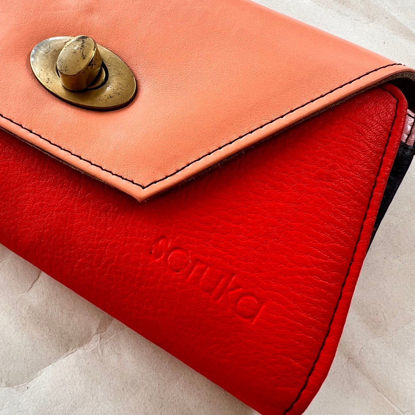 close-up of red secret clutch wallet with pink flap.