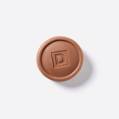 bourbon scent soap puck in a terracotta color on a white background