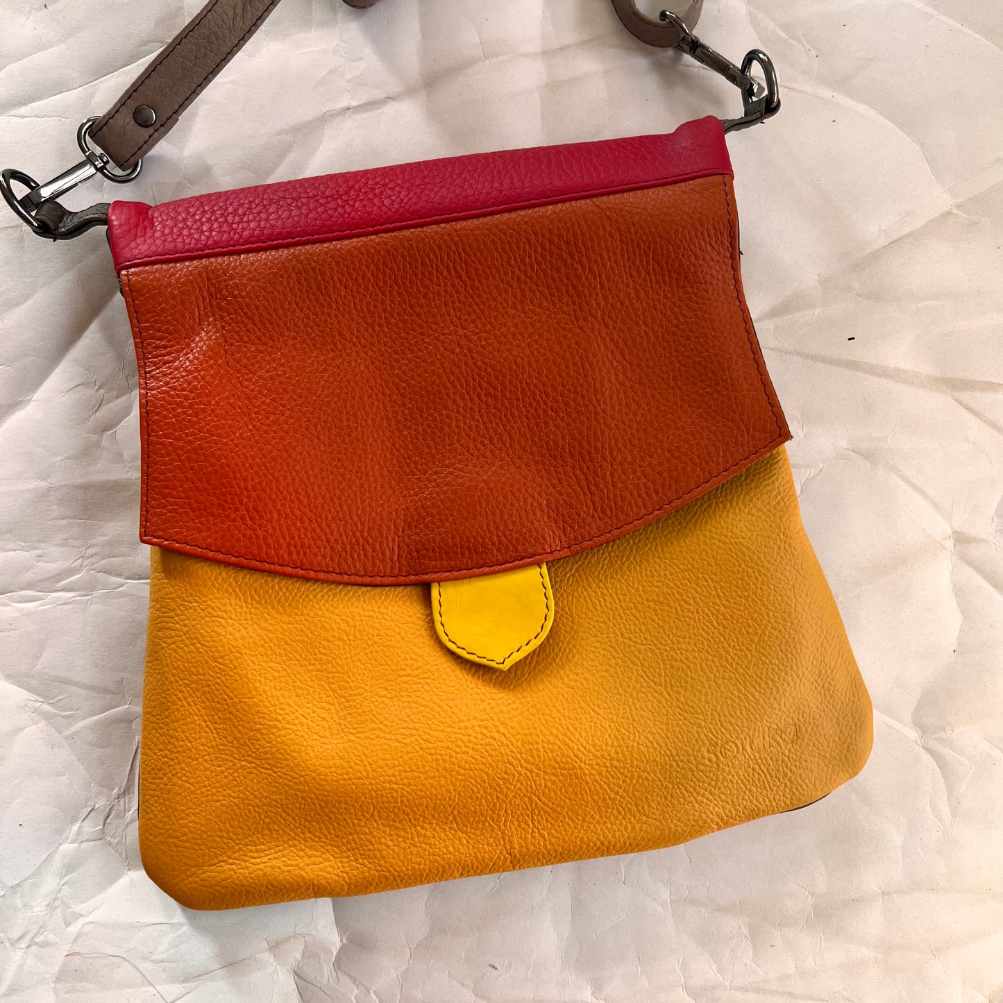 greta bag with orange flap over yellow body.