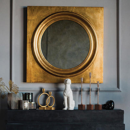 mantle arranged with assorted candlesticks and vases with a large brass framed mirror hung above it.