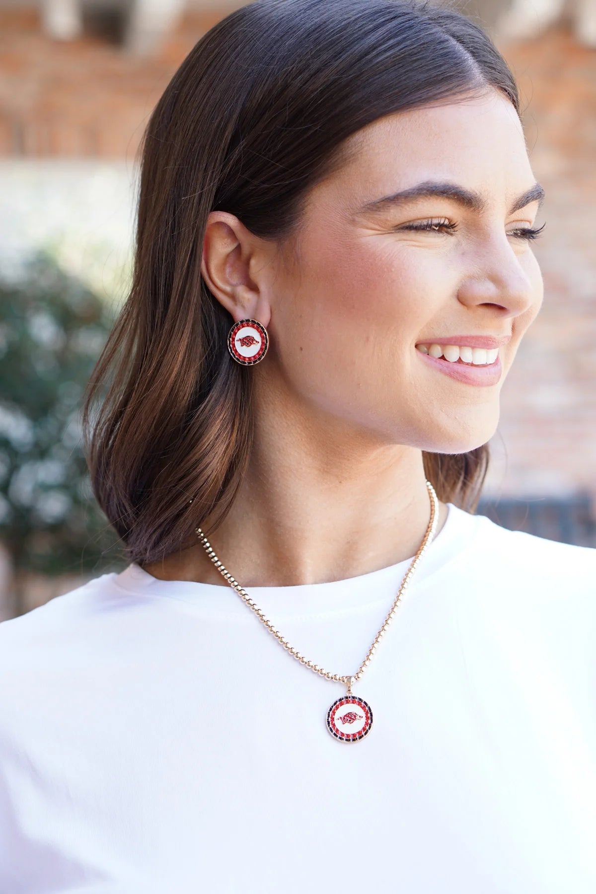 smiling person wearing Arkansas Razorbacks Disc Stud Earrings