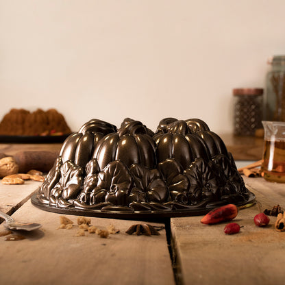 pumpkin patch bundt pan set on a wooden table with various spices and utensils.