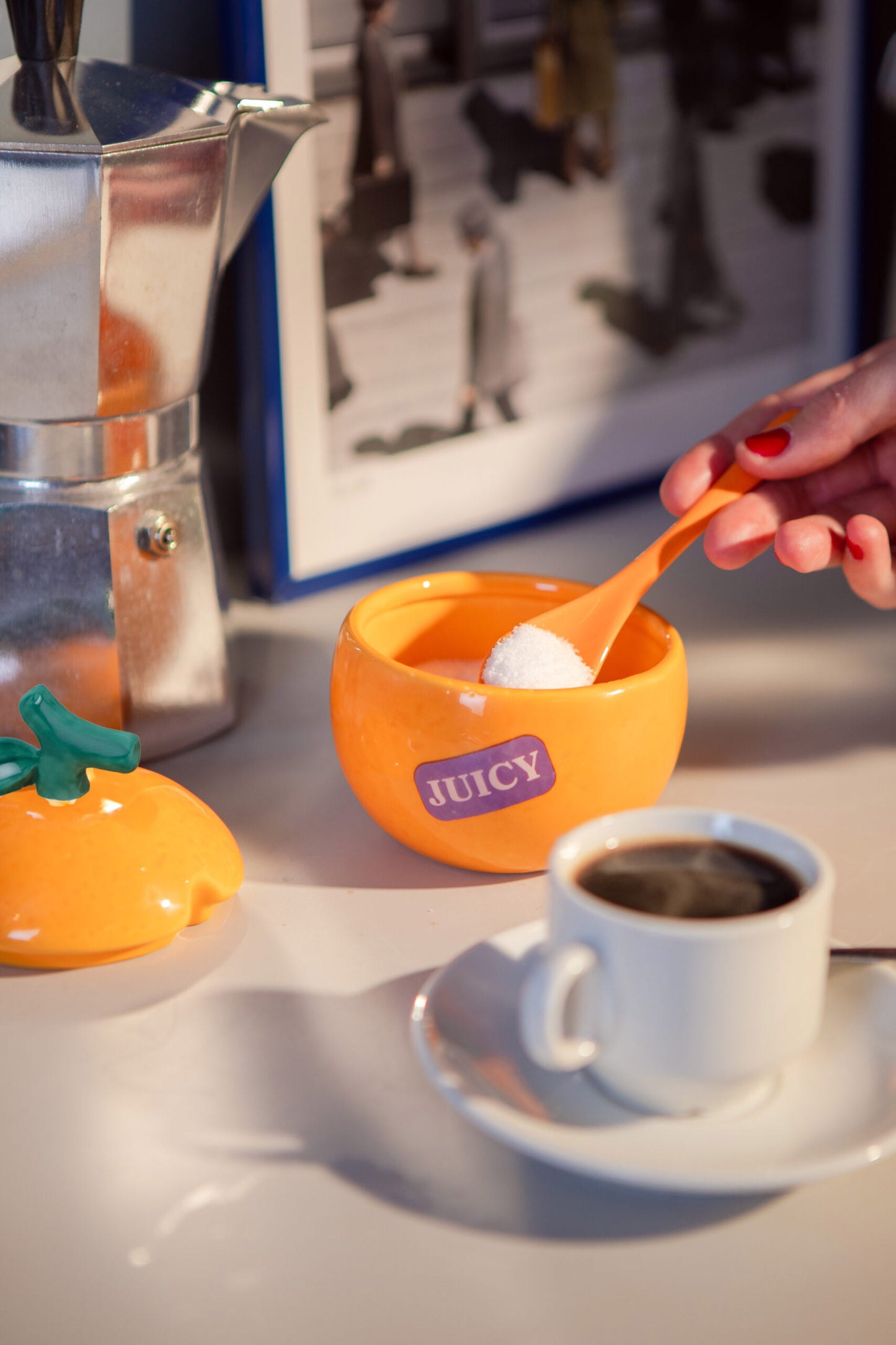 hand scooping sugar from an orange shaped sugar bowl