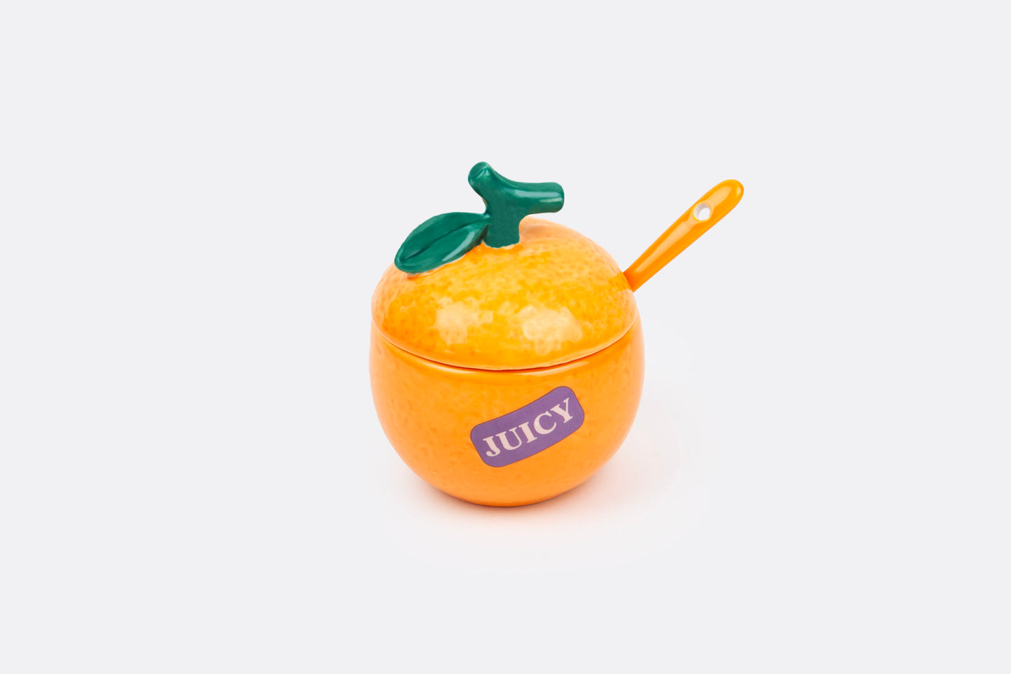 orange shaped sugar bowl with spoon in it shown on a white backgorund.