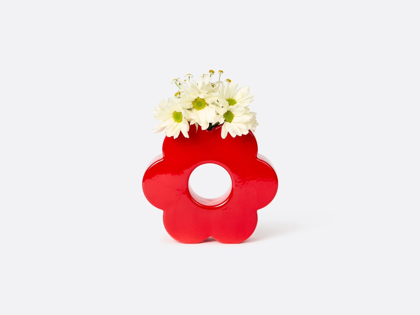 red flower shaped vase with daisies in it.