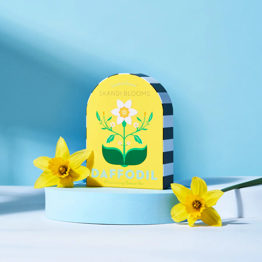 yellow box packaging with floral design set on a blue riser with blue background