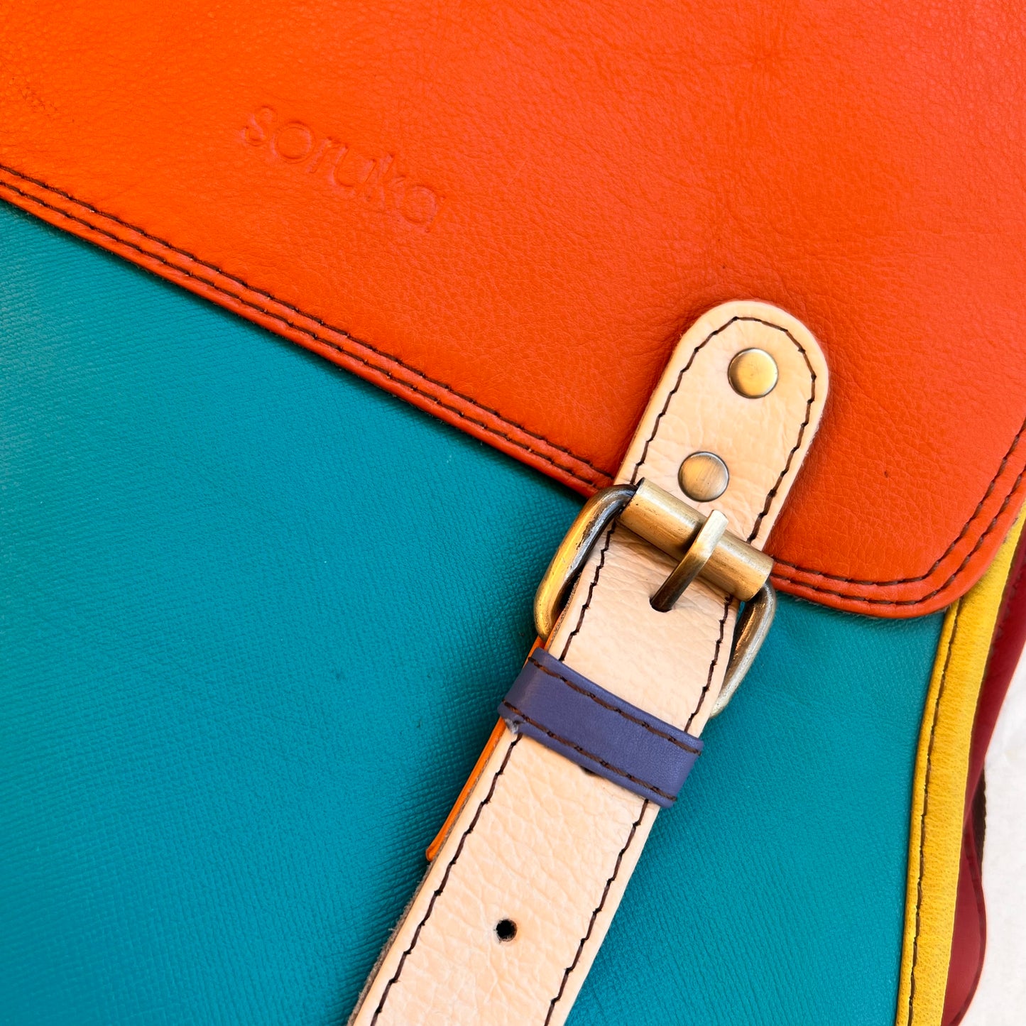 close-up of buckle tab on Turquoise jordyn backpack.