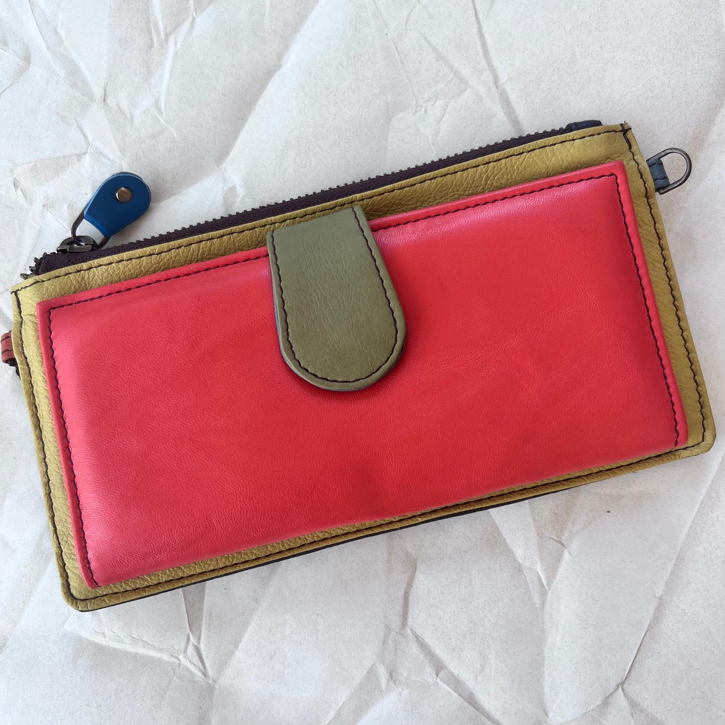 rectanglar yellow wallet with orange pocket and green tab closure.