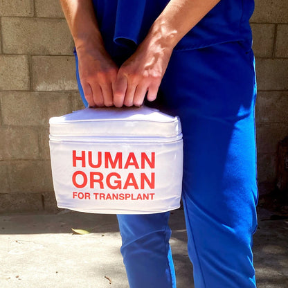 person wearing blue scrubs holding E M T meal transport bag.