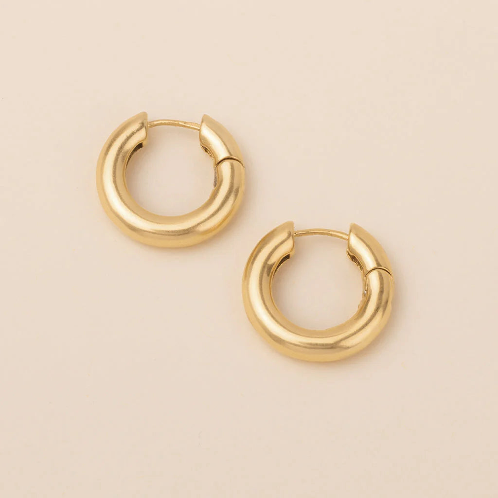 chunky gold hoops on a pink backgorund.