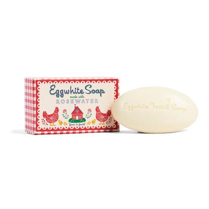 Oval bar of soap set next to its red gingham box packaging.