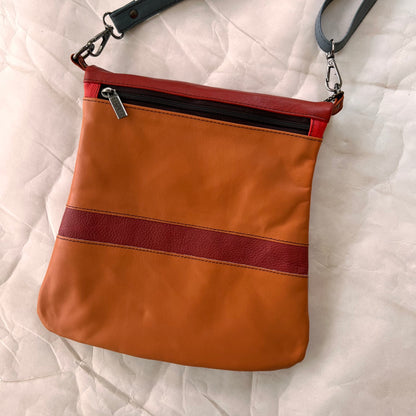 shades of orange striped greta bag with zipper across the top.