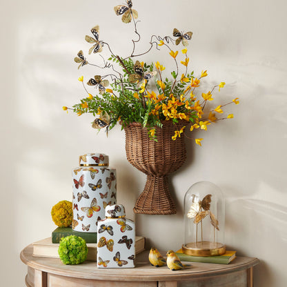 natural butterfly branch in a wicker vase with greenery and yellow flowers