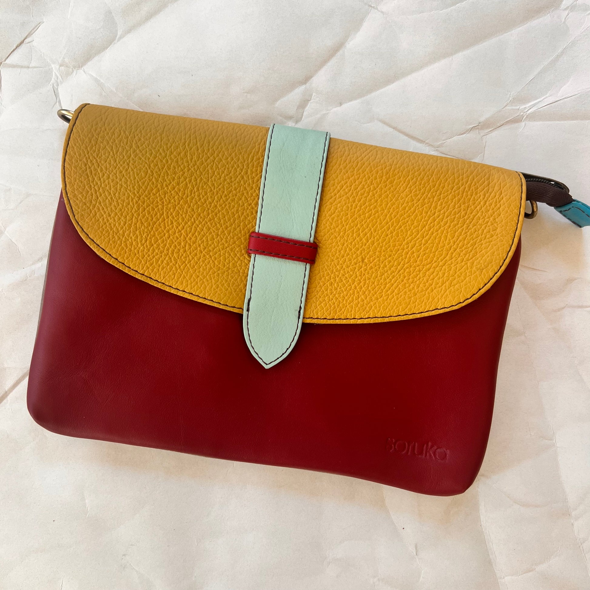 red saddle bag with mustard flap and light blue tab.