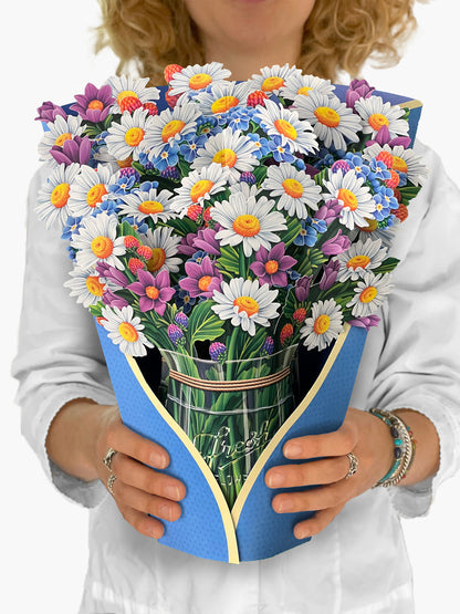 person holding Field of Daisies paper bouquet in front of their chest.