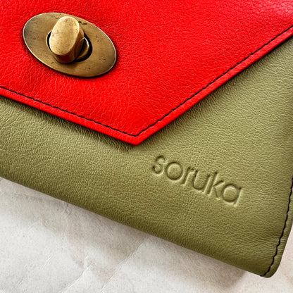 close-up of green secret clutch wallet with orange flap.