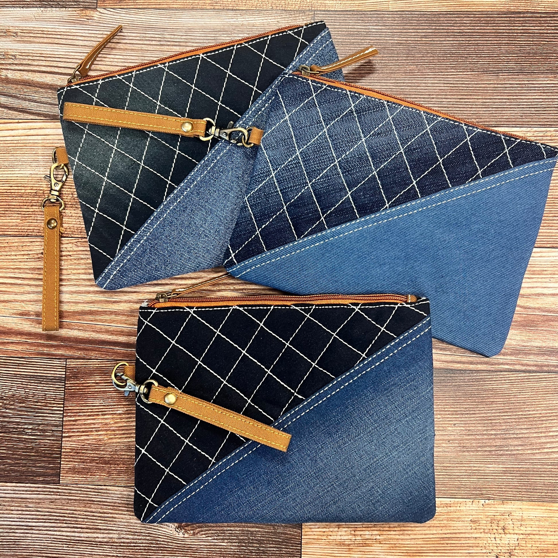 3 Denim Diagonal Wristlet Pouch arranged on a wood background.