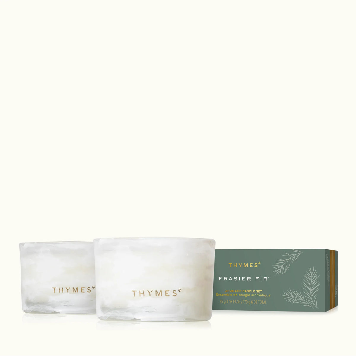 Two frosted glass candle jars with gold THYMES branding are shown in front of a muted green THYMES FRASIER FIR candle box on a clean off-white background.