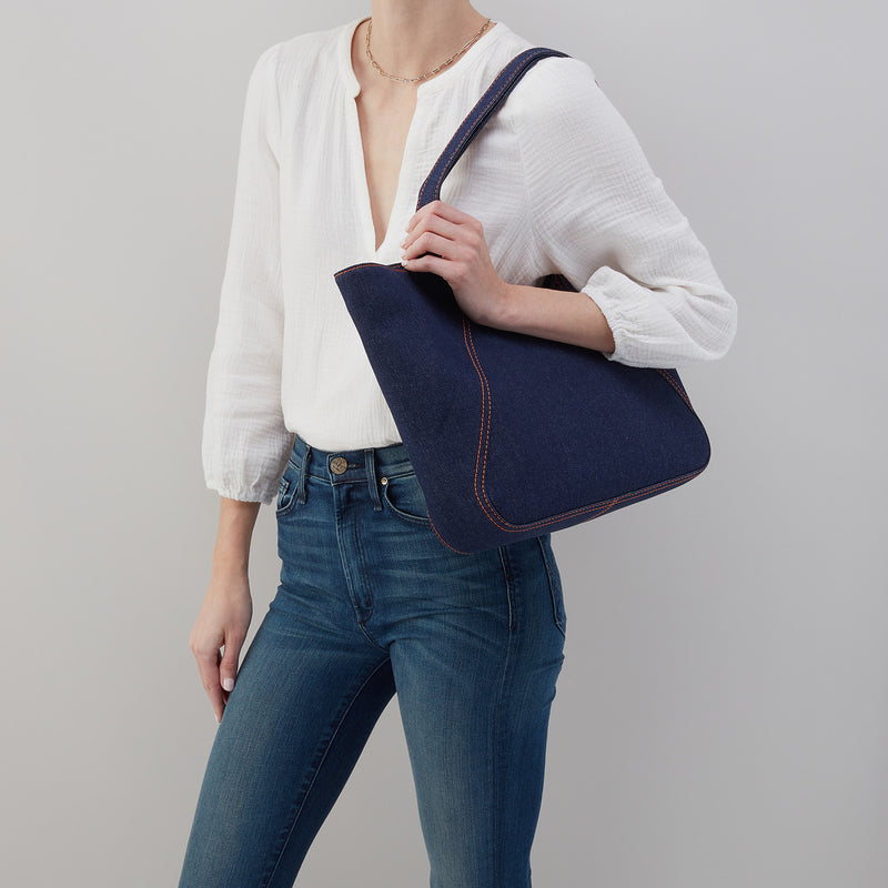 person wearing jeans and a white top with the denim bellamy tote on their shoulder.