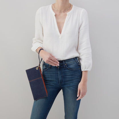 person wearing jeans and a white top with denim vida wristlet  on their wrist.
