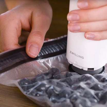 hand using vacuum pump to seal a bag filled with blueberries.