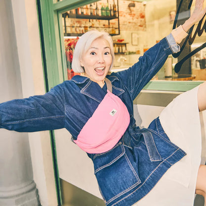 happy person wearing pink shoulder bag and denim jacket in front of a store widow