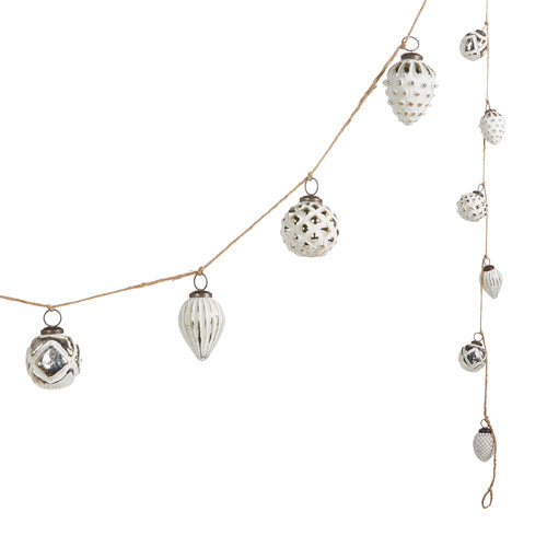 white and silver ornament garland hung on twine against a white background