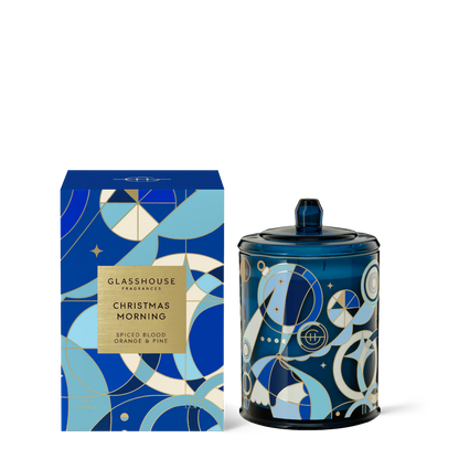 Christmas morning candle in a blue jar With an art deco design set next to it's box packaging.