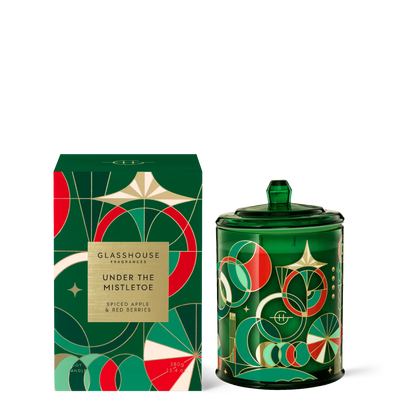 Under the mistletoe candle in green glass jar with Art Deco design set next to its box packaging.