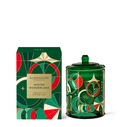 winter wonderland candle in green glass jar with art deco design set next to its box packaging.