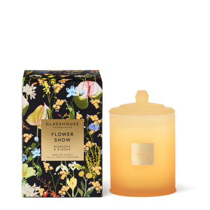 Glasshouse Flower Show candle in a pale yellow jar set next to its floral packaging on a white background