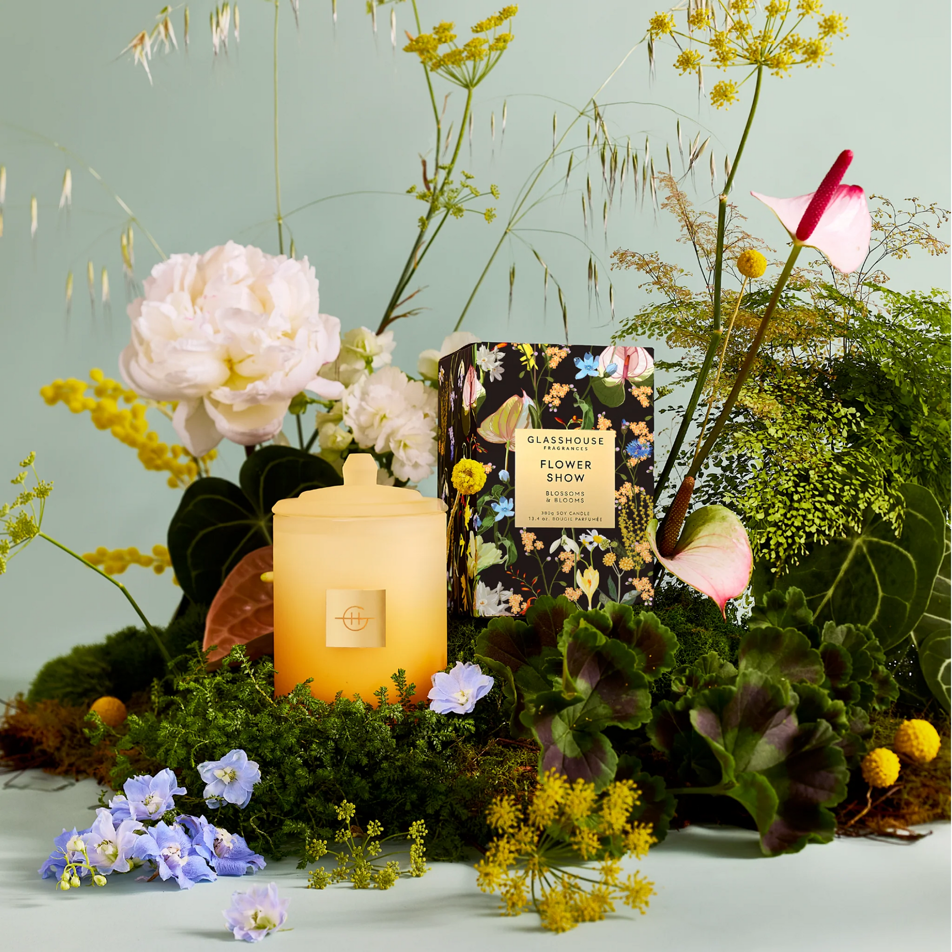 flower show Candle with a floral arrangement on a light green background
