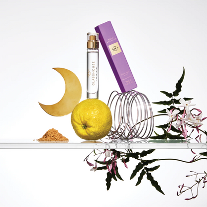 Moon and Back Eau De Parfum and its box arranged with flowers, a lemon, brown sugar, and a cresent moon shape.