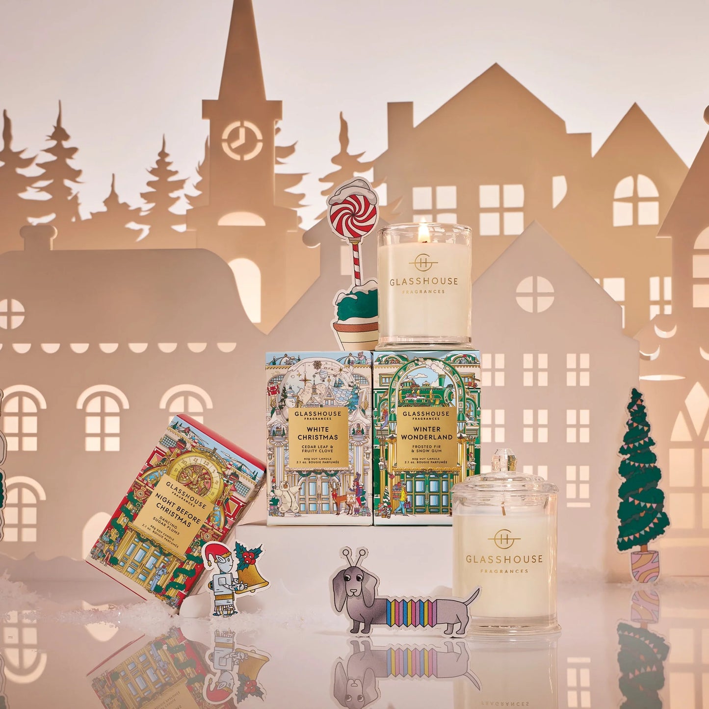 Candle collection with decorative packaging against a paper cityscape background 