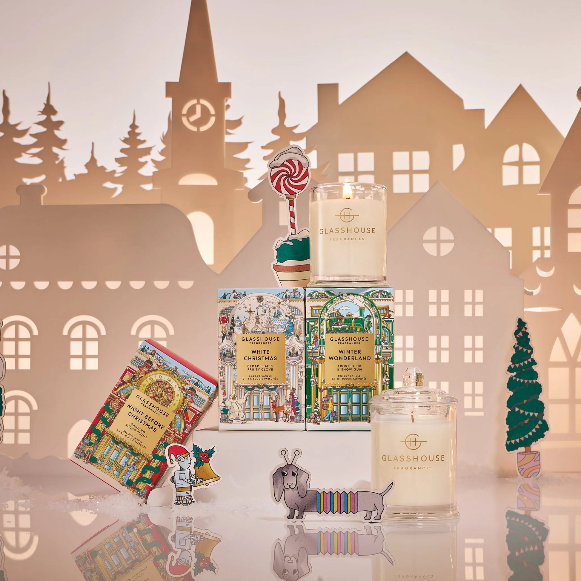Candle collection with decorative packaging against a paper cityscape background 