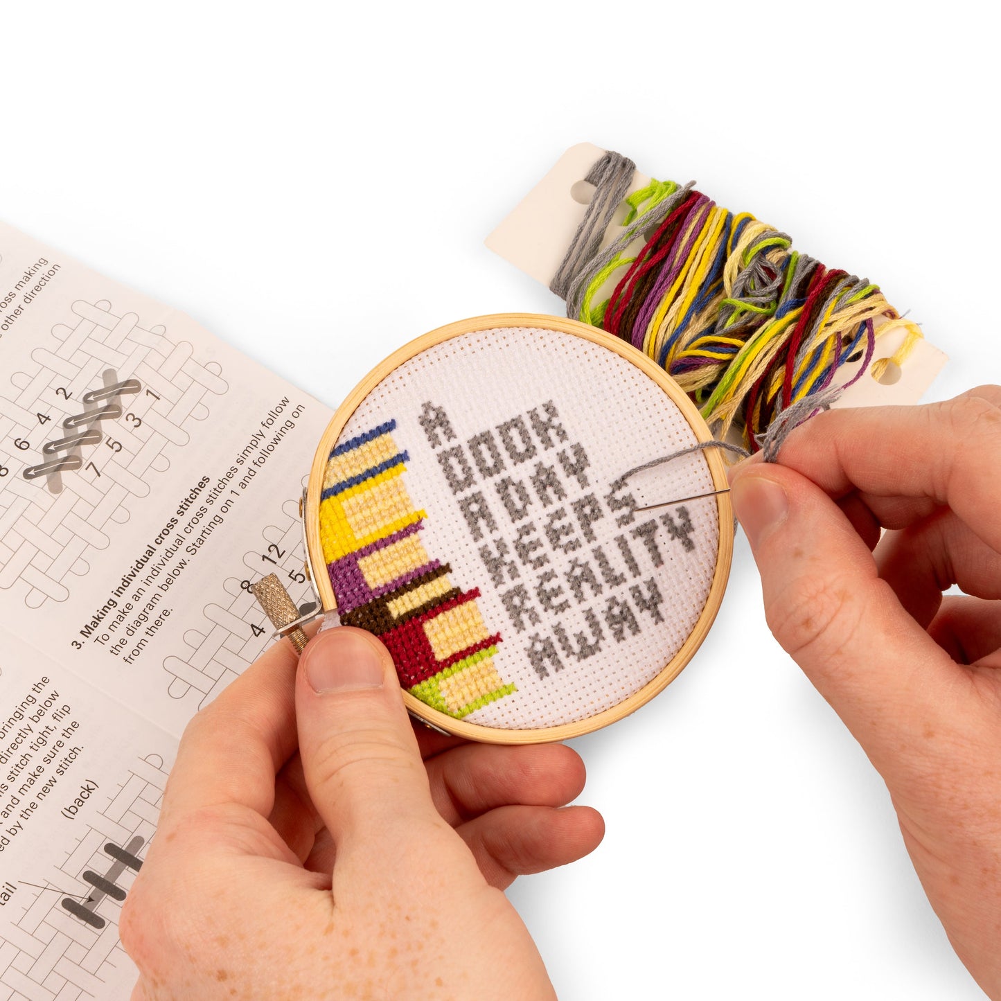 hands holding books embroidery kit