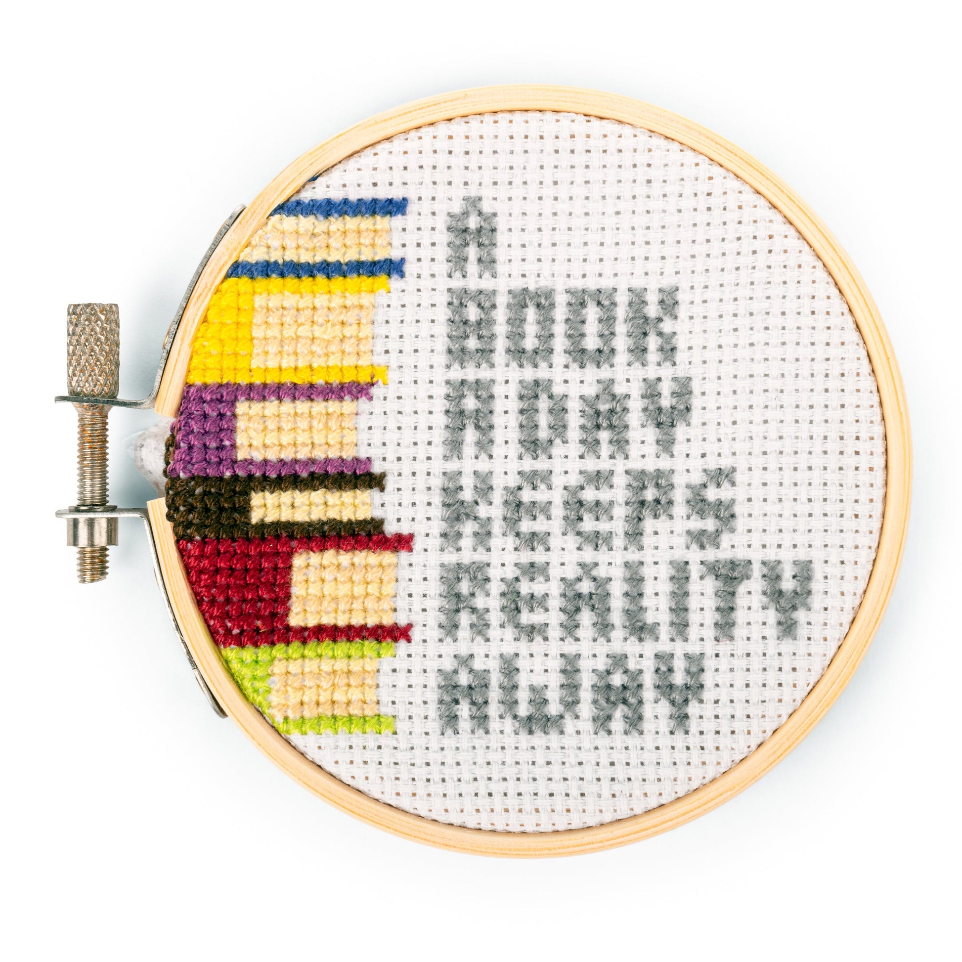 finished book embroidery kit with 'A BOOK A DAY KEEPS REALITY AWAY' stitched on it
