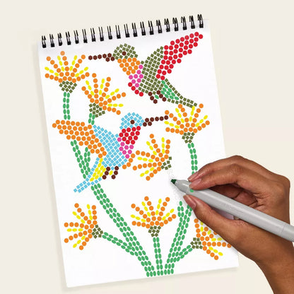 Colorful dot art being created on a spiral-bound notebook with a hand holding a marker.