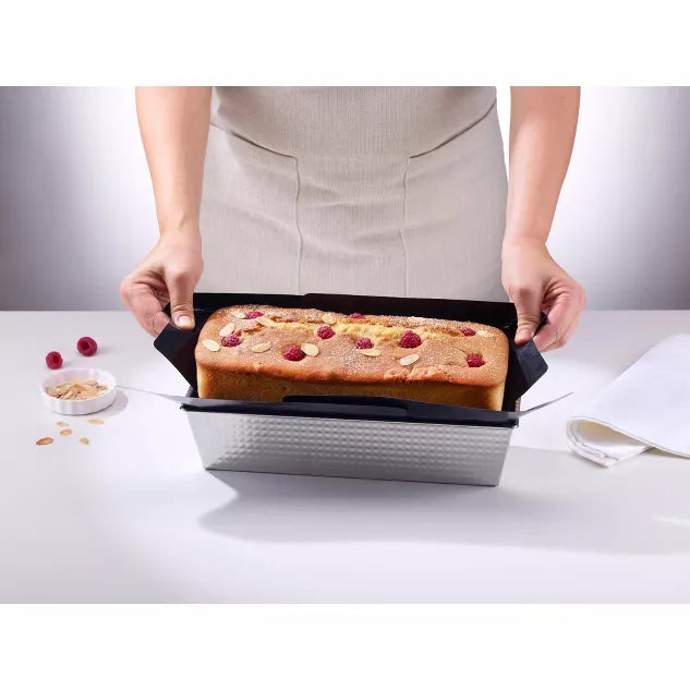 person lifting non-stick loner our of pan with baked loaf in it.