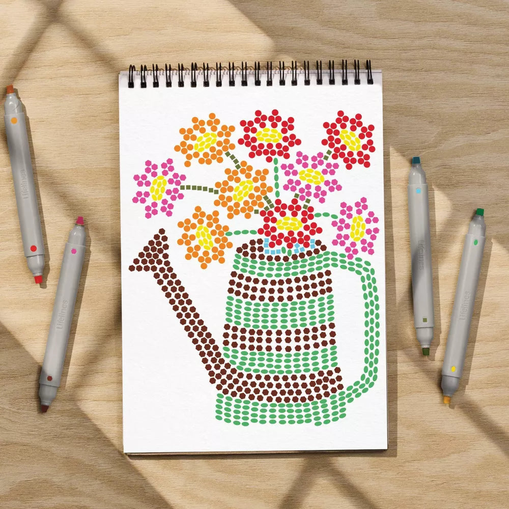 Notebook with a colorful dot illustration of a watering can and flowers on a wooden surface.