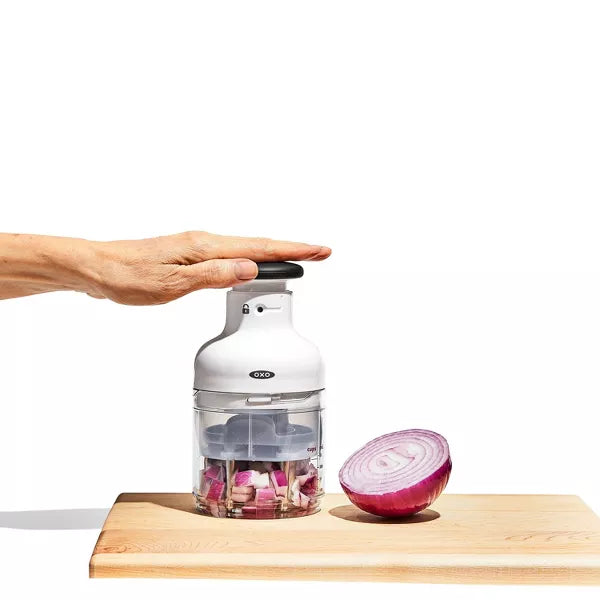 chopper being used to chop an onion on a cutting board on a white background